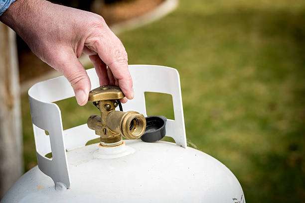 Brass Valve closed on a propane tank An image of a hand touching the valve of a propane tank.